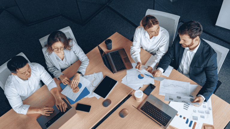 eam of professionals analyzing charts, graphs, and digital data on laptops and paper, illustrating how SEO works through strategy, collaboration, and data-driven decisions.
