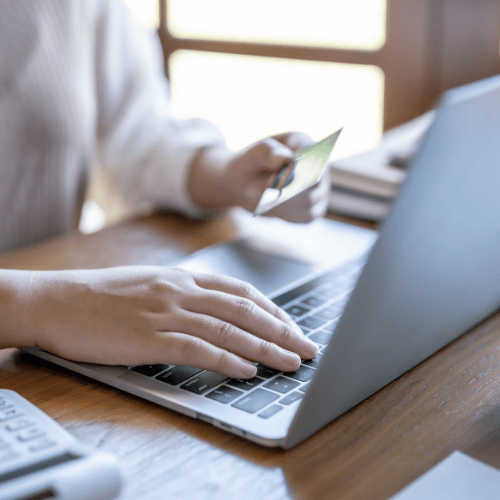 Person using a laptop while holding a credit card, representing online marketing and digital transactions.